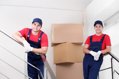 Movers carrying household items through a flat entrance in Enfield